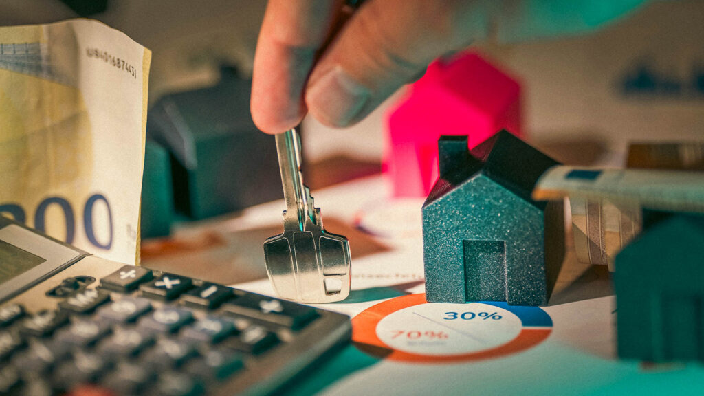 Hand balancing a key on a table with some banknotes 