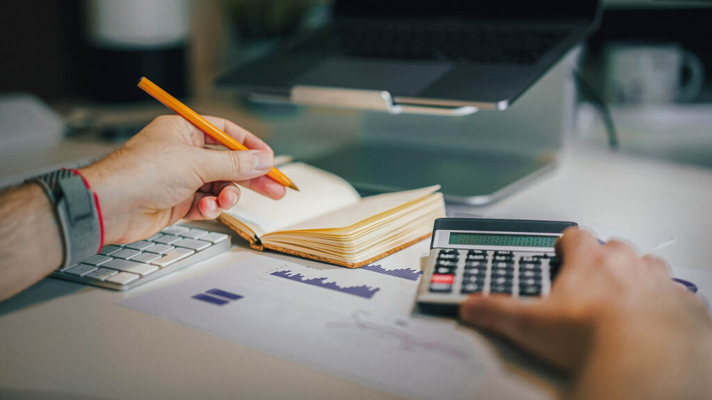 Person preparing IRPEF tax declaration using calculator and a notebook 