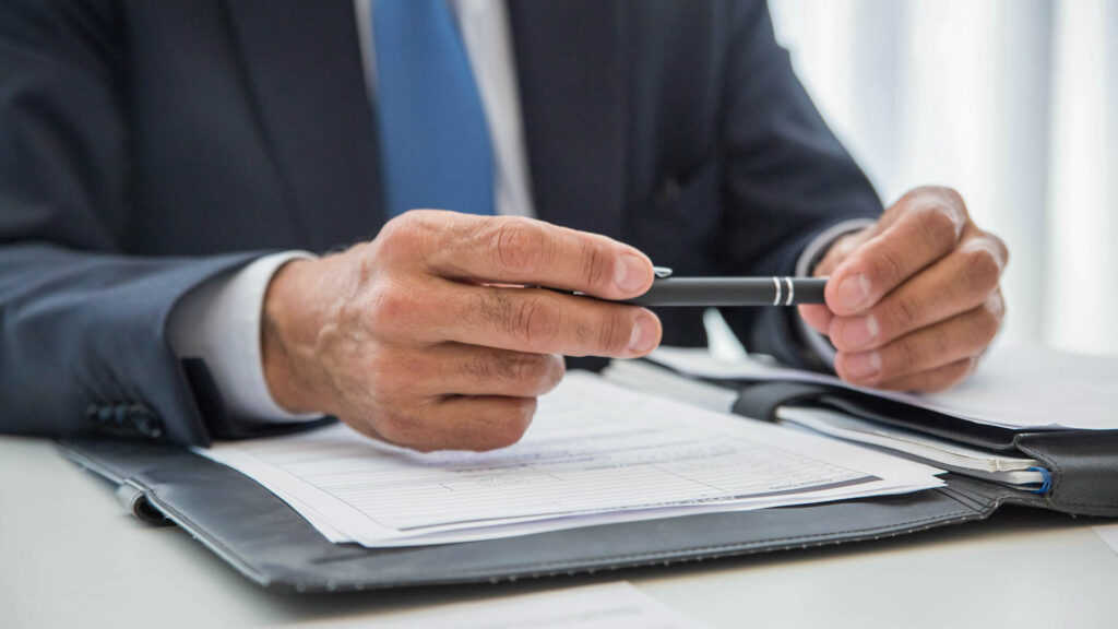 Detail of a man in suit holding a pen with both hands 